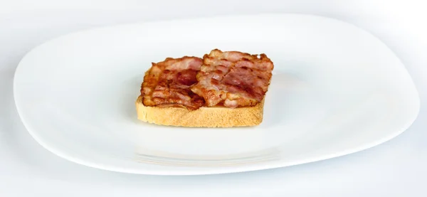 Bacon in a soft white bread roll on white plate — Stock Photo, Image