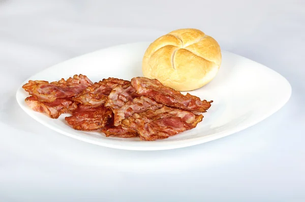 Bacon i en mjukt vitt bröd rulle på vit platta — Stockfoto