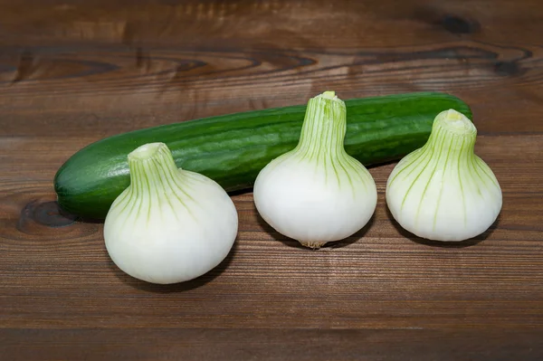 Onions and cocumber on wooden desk — Stock Photo, Image