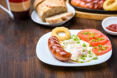 Izgara sosis, kızarmış yumurta ve domates. Zor bir gün için besleyici bir kahvaltı.