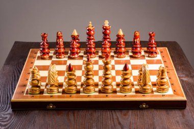 Tahta masaya serilmiş taşları olan bir satranç tahtası.