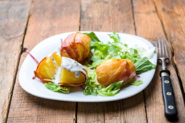 Domuz pastırmasına sarılı fırında patates ve marul karışımı.