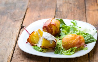 Domuz pastırmasına sarılı fırında patates ve marul karışımı.