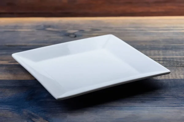 Weißer Quadratischer Teller Auf Natürlichen Tischen Aus Verschiedenen Materialien — Stockfoto