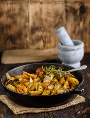 Fırında patates, soğan ve demir bir tavada otlar.
