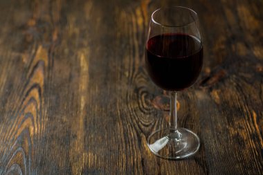 Tahta bir masanın üzerinde bir bardak şarap. Tahta bir masanın üstünde peynir tahtası.