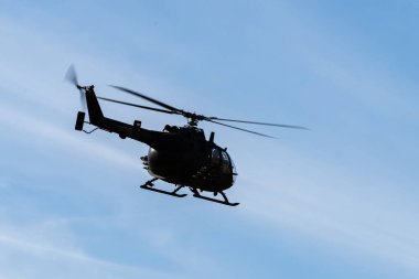 Mavi gökyüzünde bir askeri helikopterin silueti