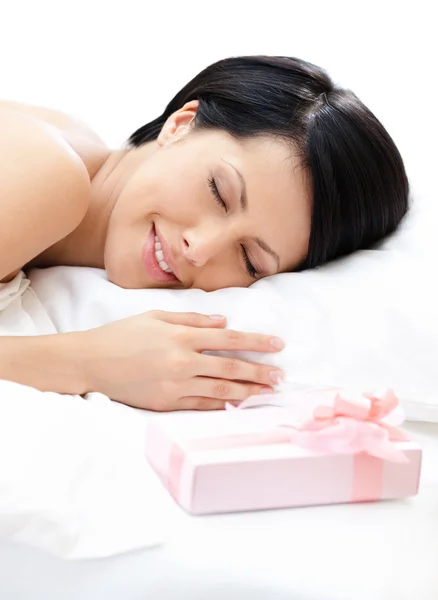 Sleeping woman and gift on the bed — Stock Photo, Image