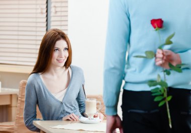 Man keeps crimson rose behind his back