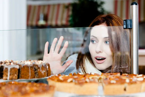 Mujer en bufanda mirando la caja de cristal de la panadería —  Fotos de Stock