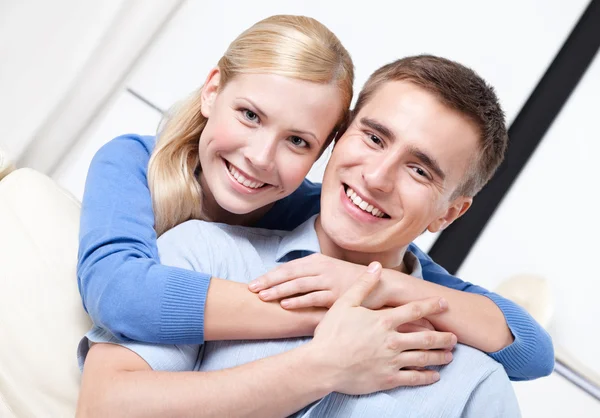 Casal feliz abraça uns aos outros no sofá — Fotografia de Stock