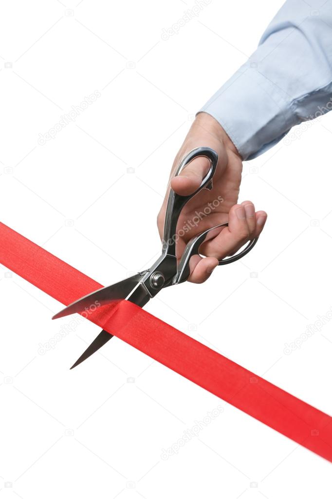 A businessman cutting a red ribbon