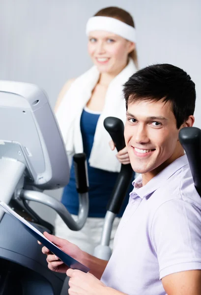 Formation de femme sur simulateurs en salle de gym avec entraîneur — Photo