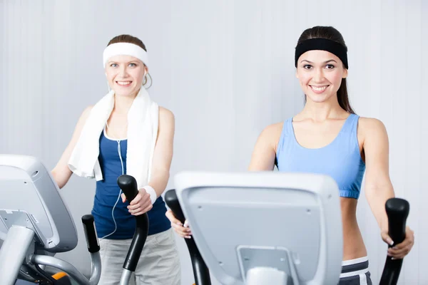 Dos mujeres entrenando en aparatos de entrenamiento en el gimnasio —  Fotos de Stock