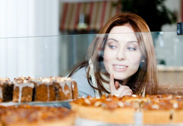 Damen i halsduk titta efter i fönstret bageri — Stockfoto