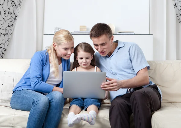 Happy family sit on the couch with laptop — Stock Photo, Image