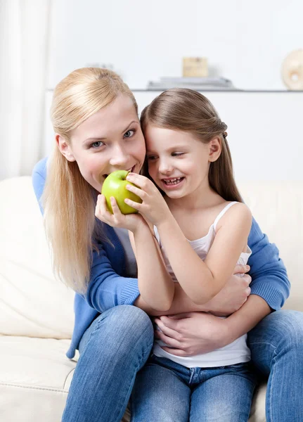 Mère souriante avec sa fille mangeant des pommes — Photo