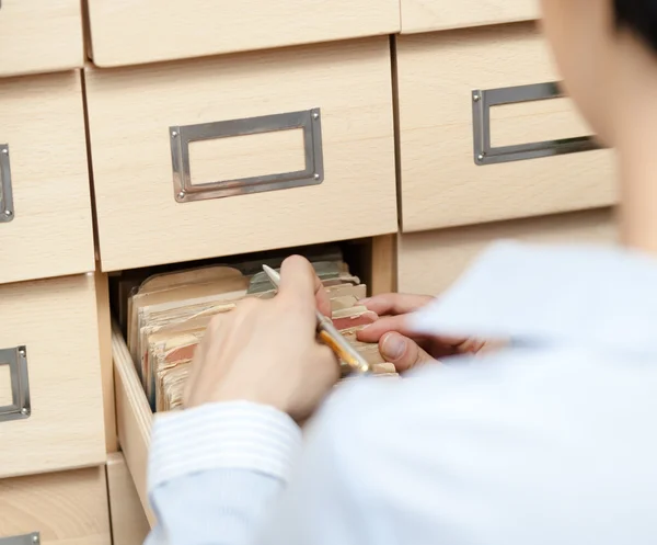 Aantrekkelijke vrouw zoekt iets in kaartenbak — Stockfoto