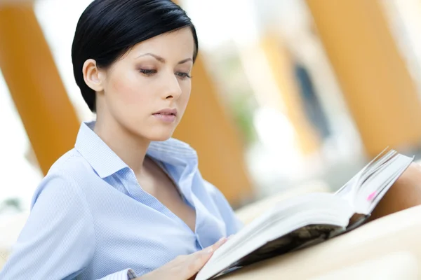 Business woman sits at the sofa reading — Stock Photo, Image