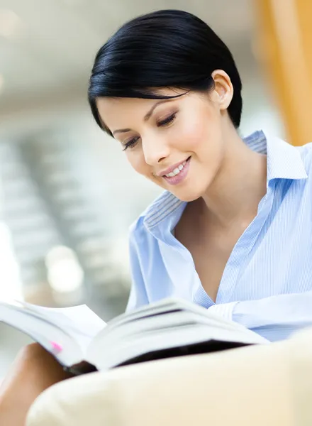 Pretty business woman rests at the sofa with book — Stock Photo, Image