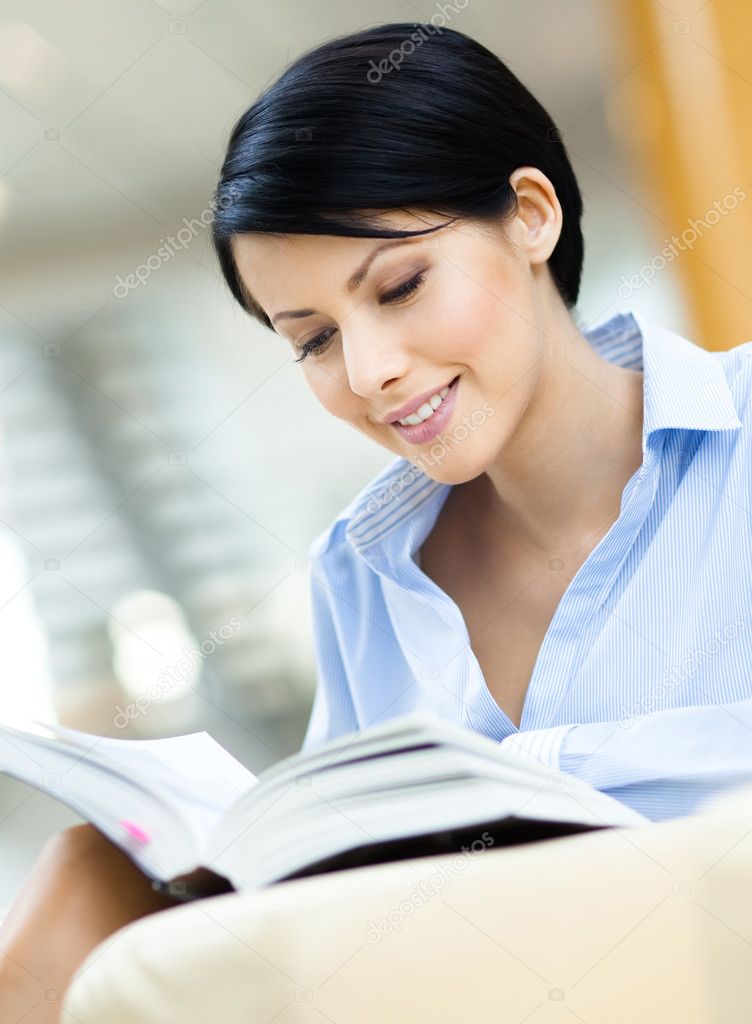 Pretty business woman rests at the sofa with book