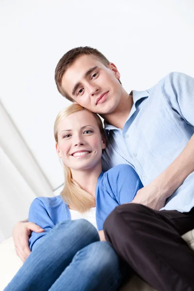 Happy couple sits on the white leather sofa — Stock Photo, Image