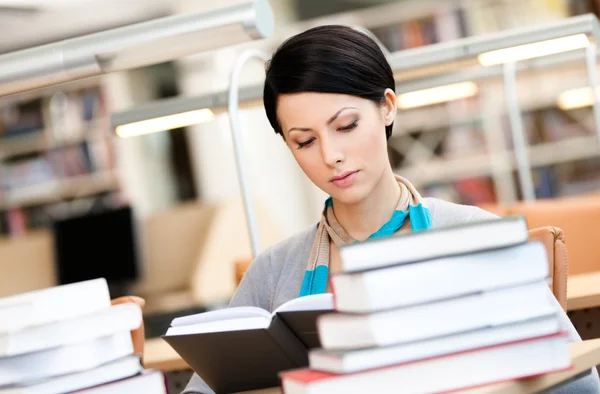 Piękna dziewczyna czyta w bibliotece — Zdjęcie stockowe
