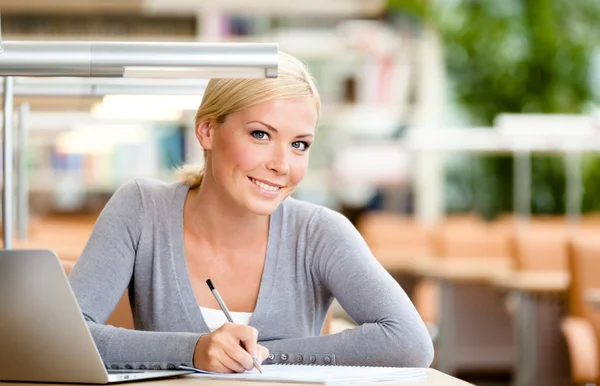 Vrouwelijke student leren aan de balie — Stockfoto