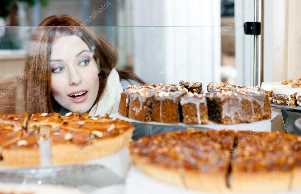 Girl in scarf looking at the bakery showcase