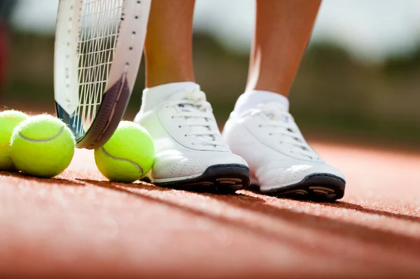 Beine des Athleten in der Nähe von Tennisschläger und Bällen — Stockfoto