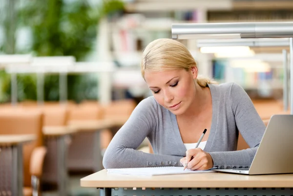 Kvinnlig student borrning vid skrivbordet — Stockfoto