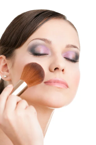 Woman applying cosmetics to her face with eyes closed — Stock Photo, Image