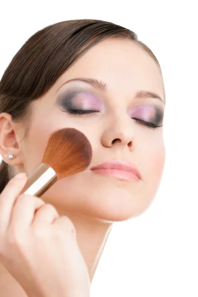 Woman applying cosmetics to her face with eyes closed Stock Photo