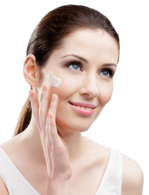 Woman applying cream on her face clipart