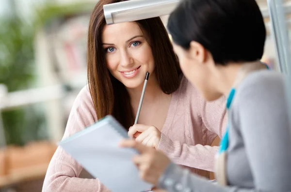 Deux filles parlent assis au bureau — Photo