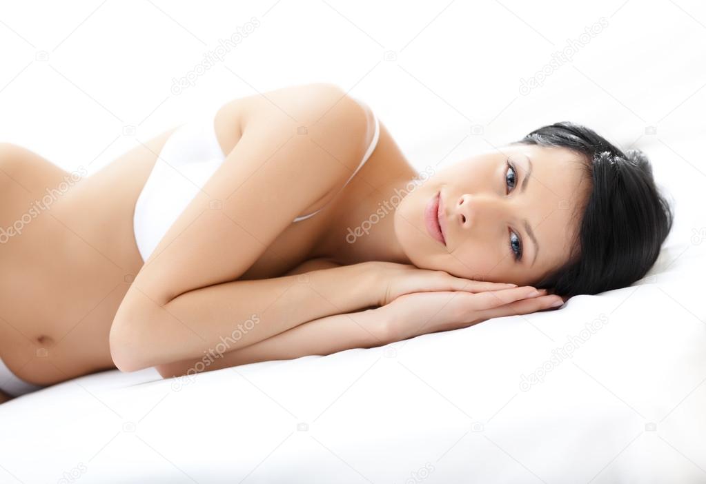 Woman in white underwear is lying in the wide bed