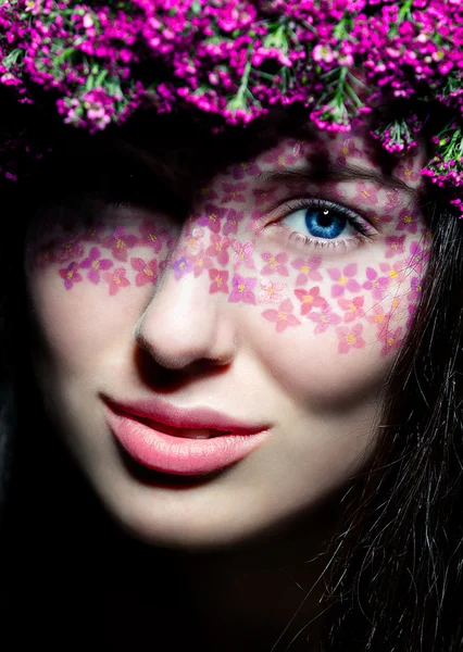 Närbild på blå-eyed kvinna med blommor — Stockfoto