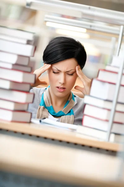 Tired woman surrounded with books — Stock Photo, Image