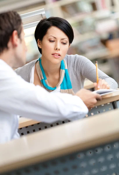 Mooie vrouw communiceert met man in de bibliotheek — Stockfoto