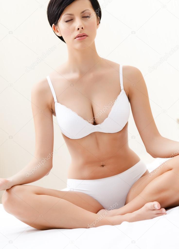 Woman meditates sitting on the wide bed