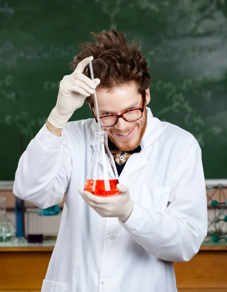 Šílený profesor něco přidá do baňky — Stock fotografie