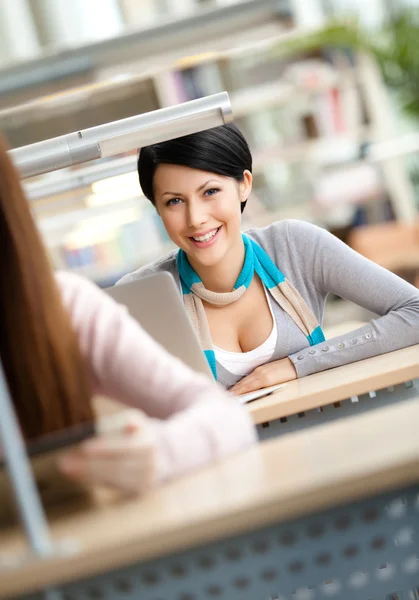 Sorridente menina senta-se à mesa — Fotografia de Stock