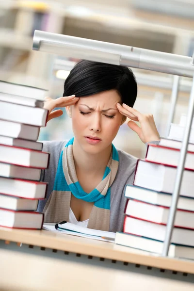 Menina cansada cercada de livros — Fotografia de Stock