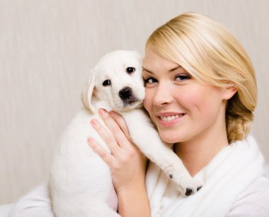 Labrador yavrusu yüzüne yakın tutan kadın