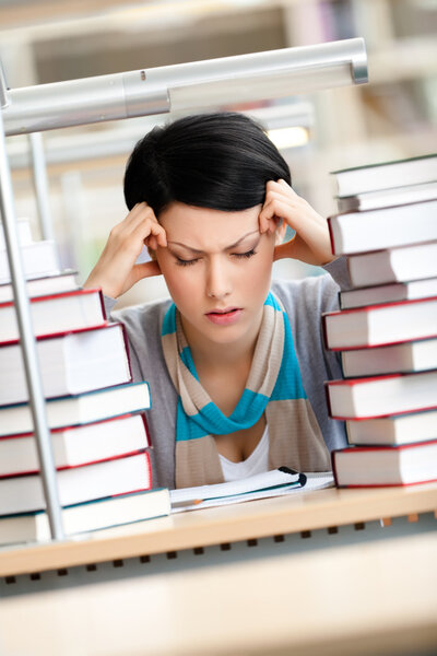 Tired young woman surrounded with books