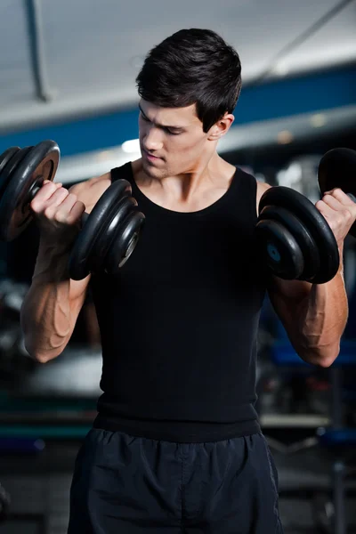 Handsome muscular man uses his dumbbells — Stock Photo, Image