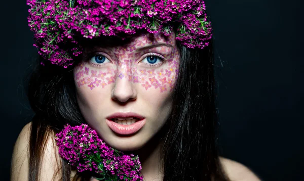 Close up of blue-eyed girl with flowers — Stock Photo, Image