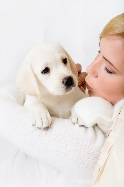 Kobieta całuje biały szczeniak labrador — Zdjęcie stockowe