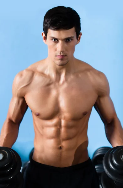 Handsome muscular man uses the dumbbell — Stock Photo, Image