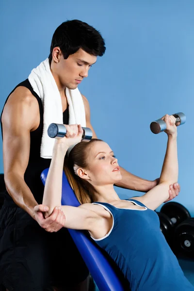 Coach helps woman to exercise with weights Stock Picture